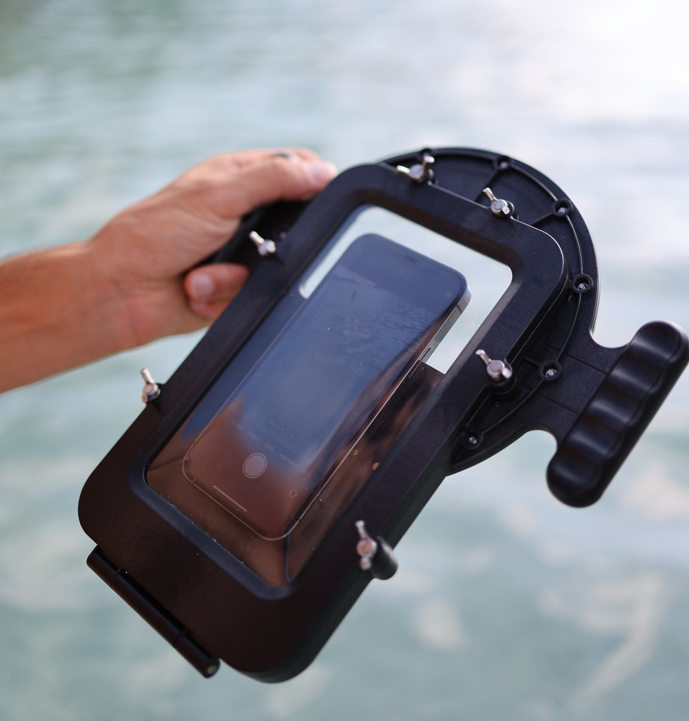 DOMEMARE Smartphone Unterwassergehäuse Rückseite: Hand hält das Case mit eingelegtem iPhone und geöffneter Kamera-App über dem Wasser.
