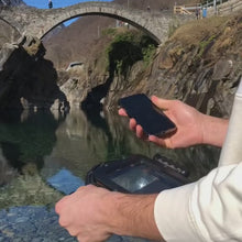 Split-Shot-Aufnahme mit dem DOMEMARE Smartphone Dome: Historische Steinbrücke über Wasser und klarer, steiniger Gebirgsfluss unter Wasser